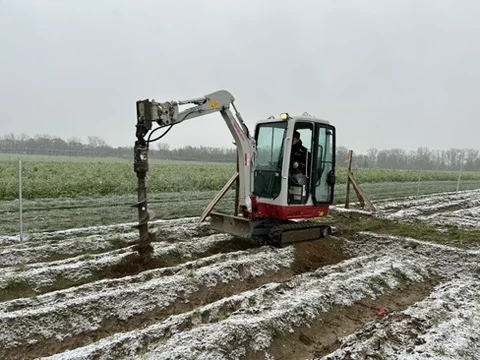 Takeuchi mit Erdbohrer setzt Pflanzlöcher entlang der Reihen